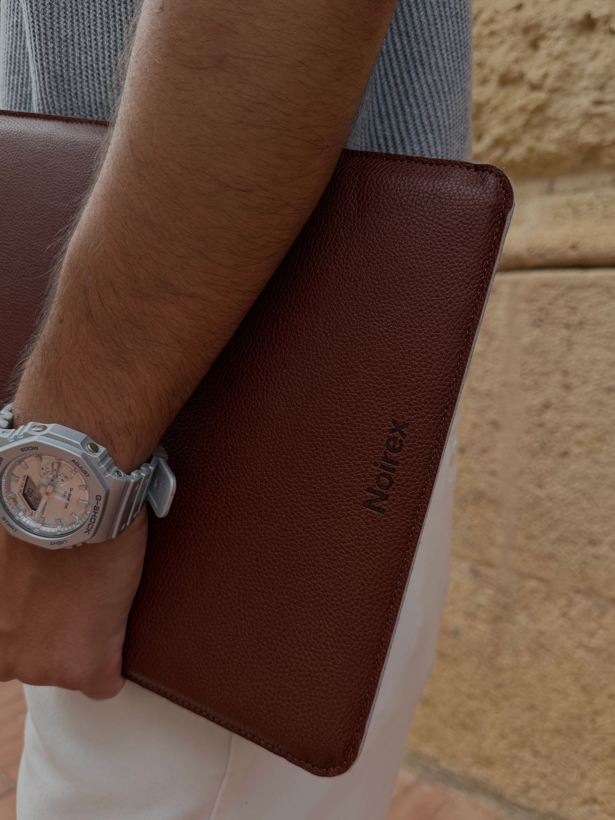 brown leather MacBook sleeve, debossed Noirex mark, lifestyle